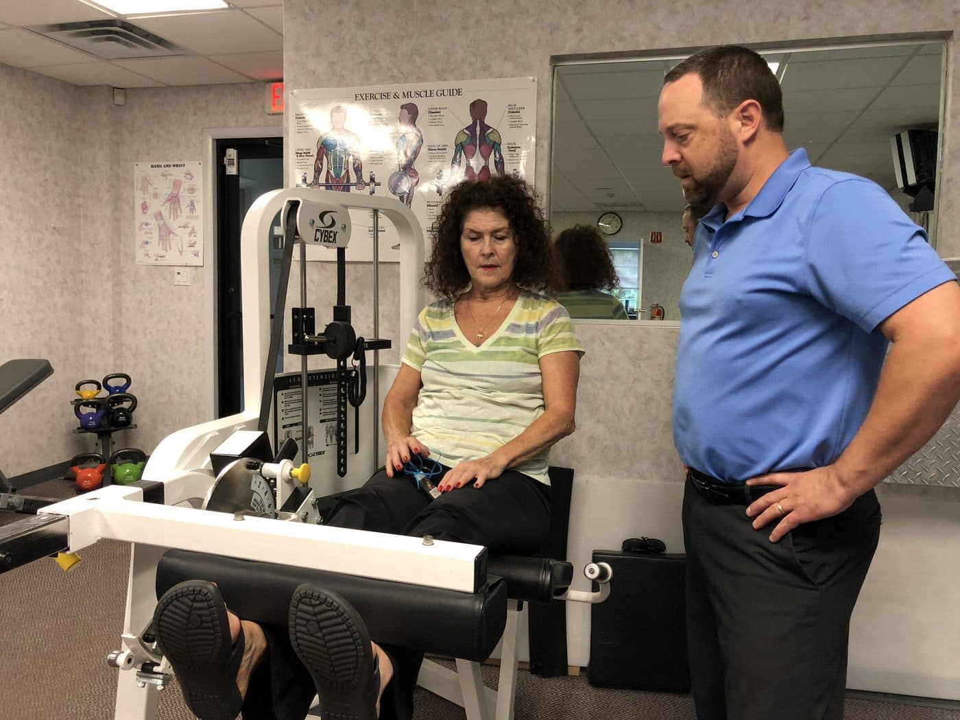 Therapist coaching a patient on a leg machine