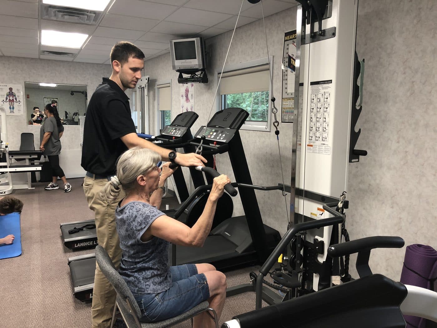 Patient working on a cable machine with a therapist nearby
