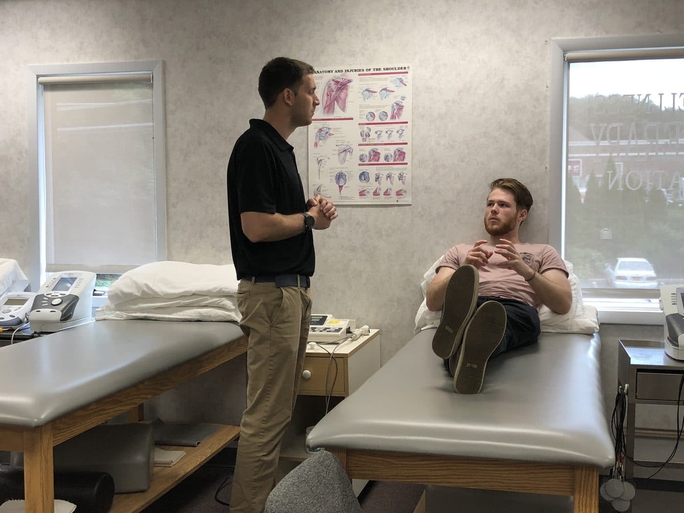 Therapist talking with a patient seated on a treatment table
