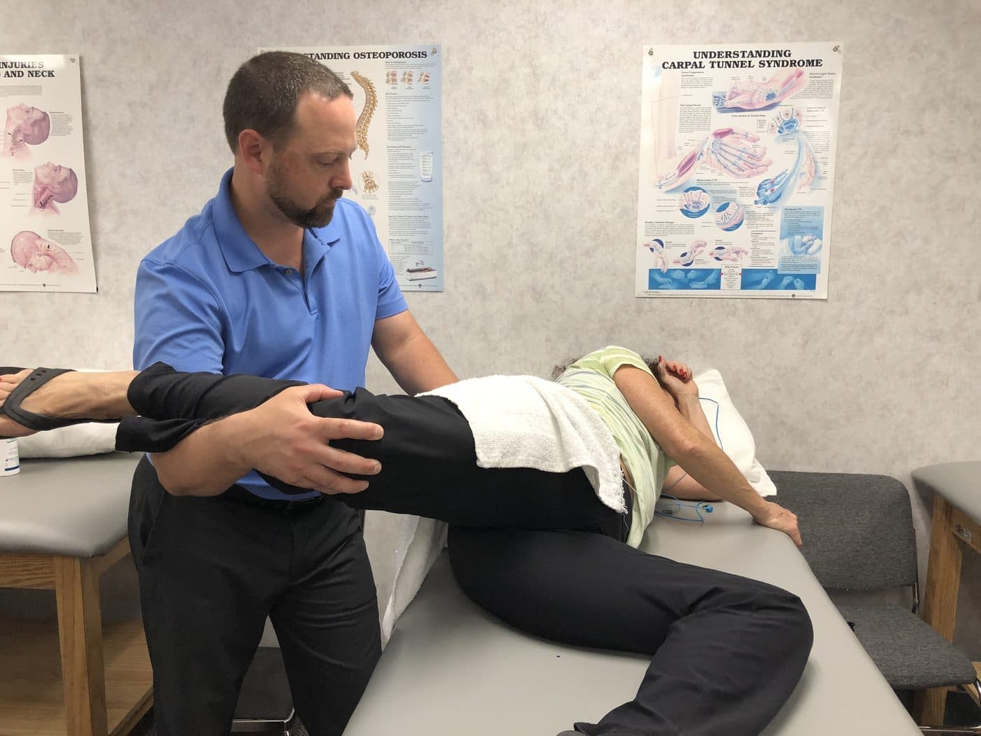 Therapist guiding a patient's leg stretch on a treatment table