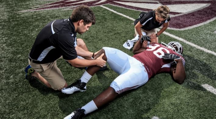 Therapist treating a football player on the field